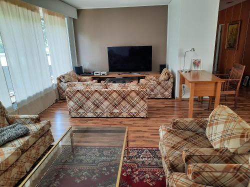 sala de estar con sofás y TV de pantalla plana. en Family House Kupittaa Diplomat, Sauna, Garden, whole house for you, en Turku