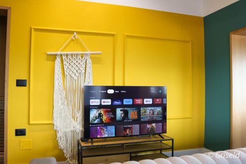 a tv in a room with a yellow wall at Drion Apartment with lake view in Pogradec