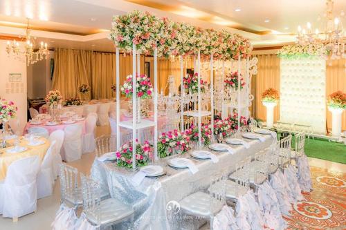un salón de banquetes con mesas blancas, sillas y flores en Aberrise Country Villa Pension Hotel, en Dumaguete