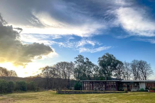 una casa in un campo con un cielo nuvoloso di Molweni - Kamberg Valley B&B a Rev Estates
