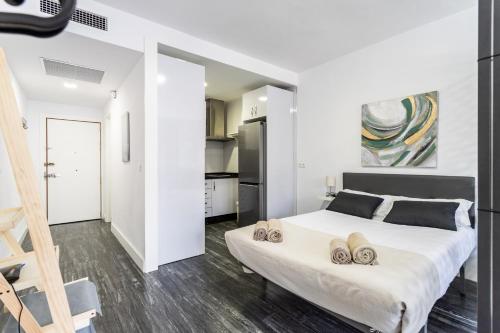 Un dormitorio con una gran cama blanca y una escalera en Sur Suites Palmeras 491, en Fuengirola