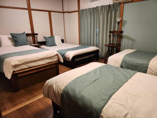 a room with three beds with green and white sheets at Thanyaporn House in Takayama