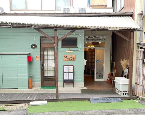 un bâtiment vert avec un panneau à l'avant dans l'établissement Thanyaporn House, à Takayama