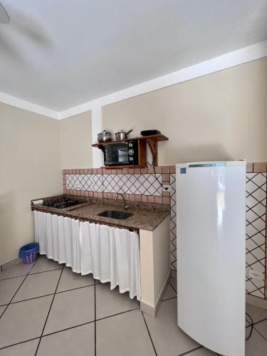 a kitchen with a counter with a sink and a refrigerator at Pousada Pangea Tropical in Arraial d'Ajuda