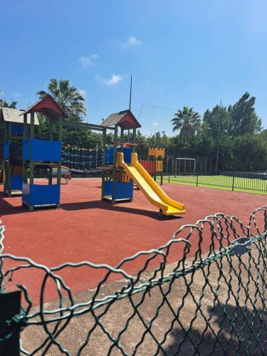 a playground with a yellow slide and a play structure at Mobil home in Fréjus