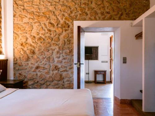 a bedroom with a bed and a stone wall at Can Pep Luis Can Pep Mortera is located in the beautiful countryside near to Playa den Bossa in Ibiza Town