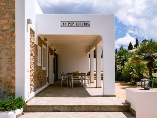 a white house with a table and chairs on a patio at Can Pep Luis Pep Mortera near to Playa Den Bossa in Ibiza Town