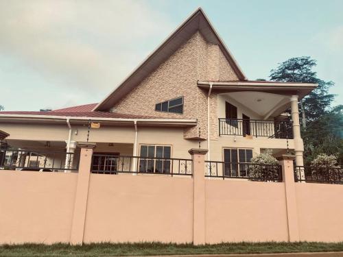 a large house with a fence in front of it at Joyous AP Guest House in Aburi