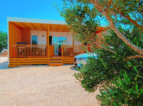 a small house with a porch and a tree at Mobile Home Drage in Drage