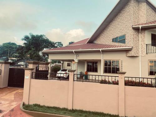 a house with a fence in front of it at Joyous AP Guest House in Aburi