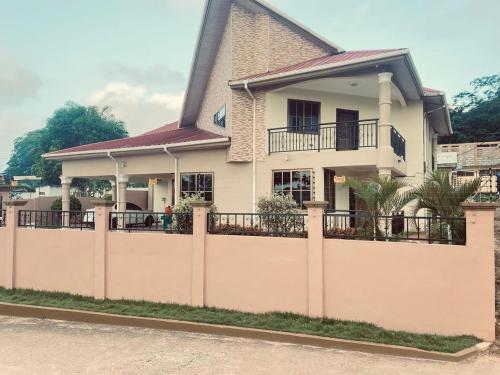 a house with a fence in front of it at Joyous AP Guest House in Aburi