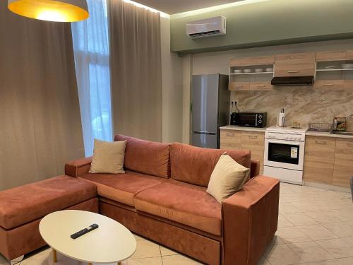 a living room with a brown couch and a kitchen at Salamina's apartments in Salamina