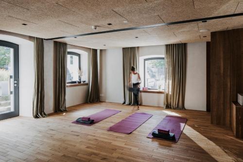 una mujer parada en una habitación con dos esterillas de yoga púrpura en Hotel Bären, en Mellau