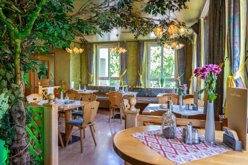 un restaurante con mesas, sillas y un árbol en Landhotel Zum Niestetal en Kassel