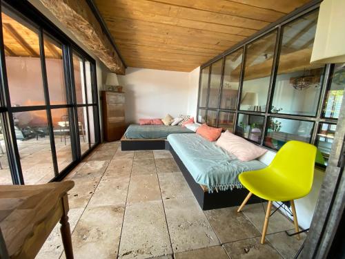 1 dormitorio con 2 camas y silla amarilla en Grande Maison d'architecte avec toit terrasse, Piscine sans vis à vis et Sauna 