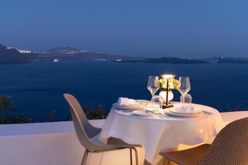 a table with a white table cloth and wine glasses at Aspaki by Art Maisons in Oia
