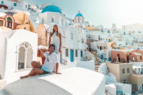 a bride and groom sitting on the edge of a building at Aspaki by Art Maisons in Oia