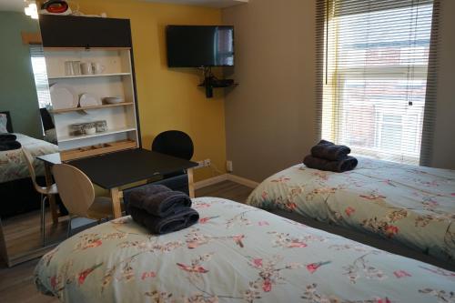 a room with two beds and a table with towels on them at Lincoln Self Catering in Lincoln