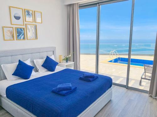 Un dormitorio con una cama azul con vista al mar. en Villa Céu e Mar, en Prazeres