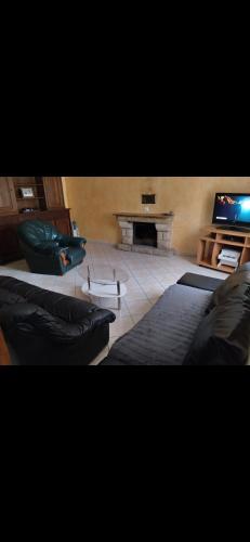 uma sala de estar com um sofá e uma televisão em Maison de campagne em Gourin