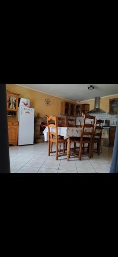 uma cozinha com uma mesa e cadeiras e um frigorífico em Maison de campagne em Gourin