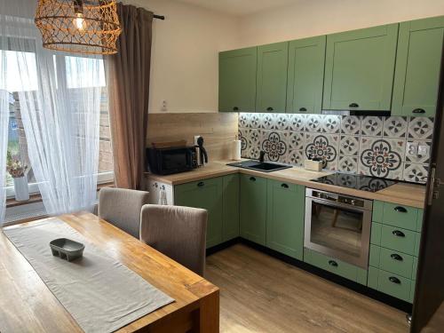eine Küche mit grünen Schränken und einem Holztisch in der Unterkunft Apartmány Silvestr in Dolní Rychnov