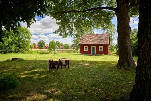 a red house with a table and a bench in a park at Kungs Starby Gård Bed and Breakfast in Vadstena