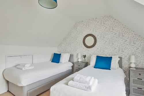 a bedroom with two beds and a mirror on the wall at The Lansdowne Boutique Rooms with Breakfast - Adults Only in Bourton on the Water