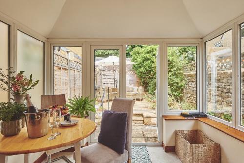a dining room with a table and chairs and windows at The Lansdowne Boutique Rooms with Breakfast - Adults Only in Bourton on the Water