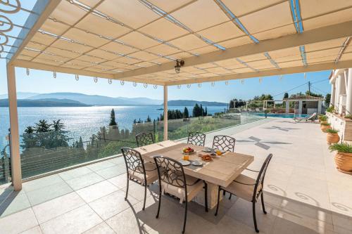 a patio with a table and chairs and a view of the water at Kalami Beach - Villa Kouloura in Kalami