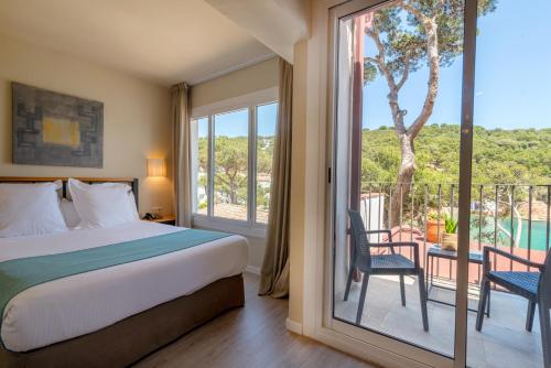 a bedroom with a bed and a balcony with a view at Hotel Hostalillo in Tamariu