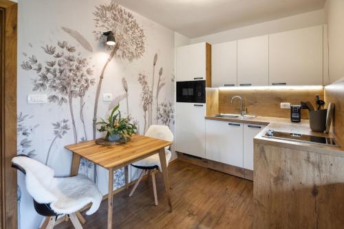 a kitchen with a wooden table and white cabinets at Hiša Vally Art in Bled