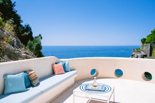 a couch with pillows and a table and the ocean at Acquachiara Seaside Luxury Villa in Amalfi Coast in Maiori