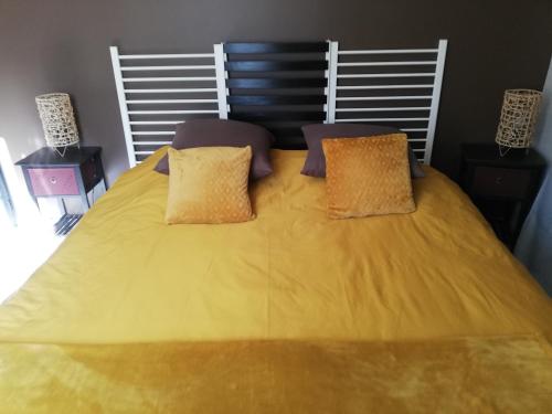 1 cama amarilla grande con 2 almohadas en Bellevue Les Carlines, en Marcillac-Vallon