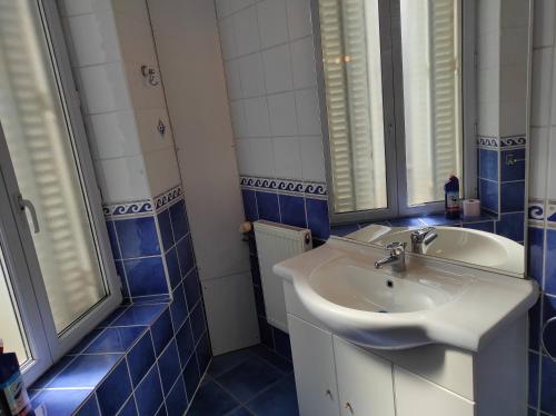 La salle de bains est pourvue de carrelage bleu, d'un lavabo et d'un miroir. dans l'établissement Bel appartement proche toutes facilités, à Nancy