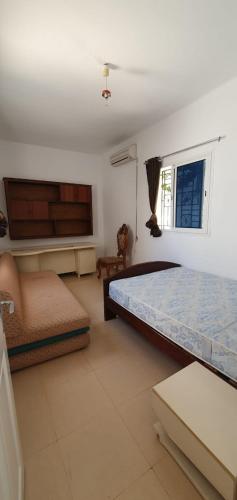 a bedroom with a bed and a couch and a window at Chouette villa au bord de la plage hergla in Sousse