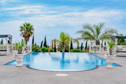 a large swimming pool with palm trees in the background at Villa La Perla in Licata