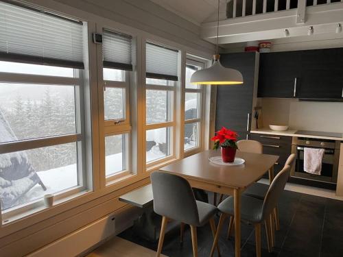 a kitchen with a table and chairs and windows at Voss - Flott hytte i Bavallen in Skulestadmo