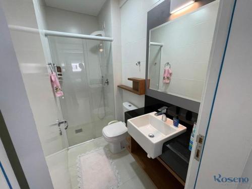 uma casa de banho com um lavatório, um chuveiro e um WC. em Apartamento a poucos passos do mar em Governador Celso Ramos