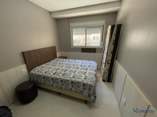 um pequeno quarto com uma cama e uma janela em Apartamento a poucos passos do mar em Governador Celso Ramos