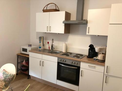 a kitchen with white cabinets and a stove top oven at Ferienwohnung Schlossberg 1 in Wirsberg