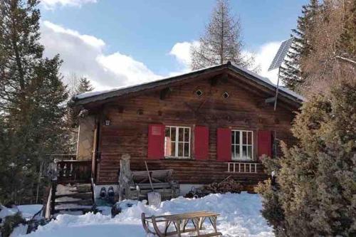 a log cabin with red doors in the snow at Beautiful Swiss chalet with breathtaking views and a sauna 