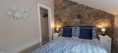 sypialnia z łóżkiem z niebieskimi poduszkami i kamienną ścianą w obiekcie Frontview Cottage - Sleeps 6 w mieście Ballynahinch