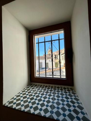 a room with a window and a checkered floor at Apartamento La Medina in Guadix