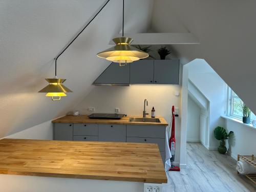 una cucina con bancone, lavandino e luci di Loftlejlighed i centrum a Ringkøbing