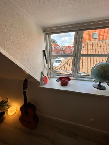 ein Fenster in einem Zimmer mit einer Gitarre auf einem Regal in der Unterkunft Loftlejlighed i centrum in Ringkøbing