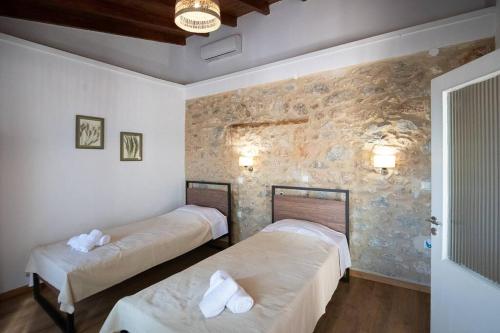 two beds in a room with a stone wall at Traditional stone house in Neokhórion