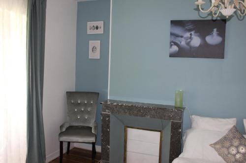 a bedroom with a bed and a chair and a chandelier at La Charentaise des Lilas in Saint-Léger