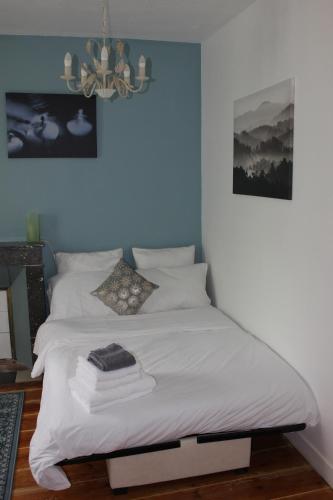 a white bed in a room with a chandelier at La Charentaise des Lilas in Saint-Léger