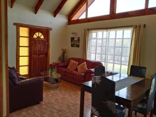 ein Wohnzimmer mit einem roten Sofa und einem Tisch in der Unterkunft Conectar con la naturaleza te hará más feliz in Melipilla